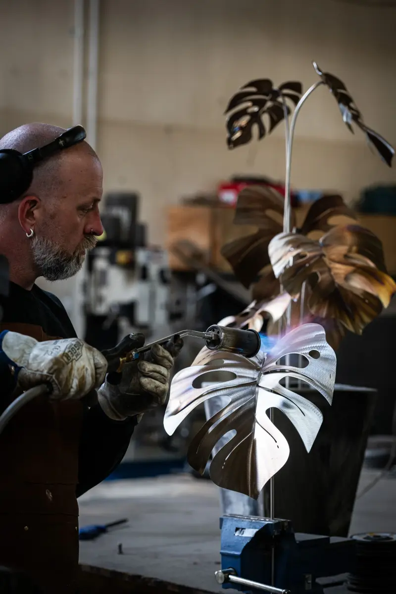 alt="Artist torching a large monstera leaf"