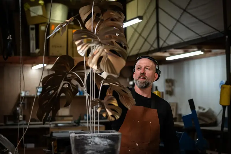 Artist with completed monstera sculpture